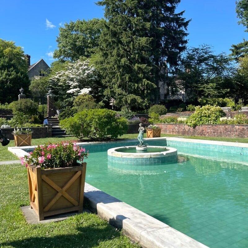 View of a pool and trees at Planting Fields, one of the best Long Island gardens in New York.